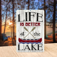 Load image into Gallery viewer, Rustic Life Is Better at the Lake Metal Sign displayed outdoors near a tranquil lake at sunset, adding charm to cabins, docks, and waterfront retreats.
