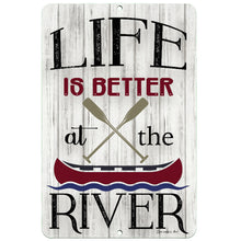 Load image into Gallery viewer, Dyenamic Art Life Is Better at the River Metal Sign – Rustic river-themed decor featuring a red canoe, crossed paddles, and a distressed wood-style background, perfect for cabins and waterfront homes.
