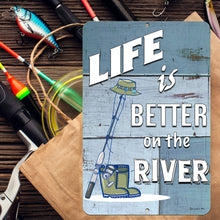 Load image into Gallery viewer, Detailed close-up of the Life Is Better on the River Metal Fishing Sign, showcasing a fisherman casting a line, vintage-style typography, and a weathered wood-style background.
