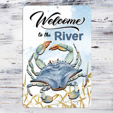 Load image into Gallery viewer, Detailed close-up of the Welcome to the River Metal Sign, showcasing a vibrant blue crab illustration, watercolor-style accents, and a distressed wood-style background for a coastal aesthetic.
