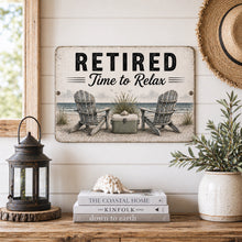 Load image into Gallery viewer, Decorative sign with 'Retired Time to Relax' text on a wall with books and decor items below.

