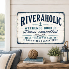 Load image into Gallery viewer, Riveraholic metal sign displayed in a rustic river house living room with waterfront decor and cozy cabin styling
