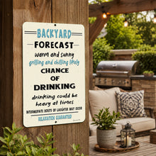 Load image into Gallery viewer, A rectangular metal sign with a cream background and black and light blue text reading 'BACKYARD FORECAST' and a humorous weather-style message about drinking, mounted on a wooden post in an outdoor patio setting.

