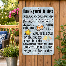 Load image into Gallery viewer, A rectangular metal sign with a weathered light blue background and black text reading 'Backyard Rules' with humorous phrases and small illustrations, hanging on a wooden fence in an outdoor garden setting.
