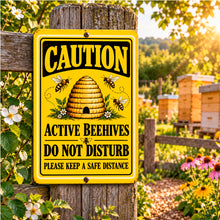 Load image into Gallery viewer, Active Beehives warning sign mounted near a garden beekeeping area with colorful flowers, greenery, and a rustic wooden fence.

