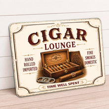 Load image into Gallery viewer, A rectangular vintage-style metal sign for a 'Cigar Lounge' leans against a white paneled wall on a light wood floor. The sign features an aged cream background with dark brown and black text, an illustration of an open cigar box with cigars, and decorative distressed borders.

