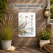 Load image into Gallery viewer, Decorative metal sign with a crane design and 'Welcome' text on a wooden wall with plants and lantern.
