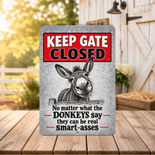Load image into Gallery viewer, Funny donkey Keep Gate Closed metal sign displayed in a warm rustic barn setting on a wooden surface
