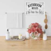 Load image into Gallery viewer, Bathroom Rules Sign elegantly placed above a wooden vanity with soft pink flowers, adding a stylish touch to guest bathrooms and powder rooms.
