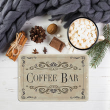 Load image into Gallery viewer, Classic Coffee Bar Metal Sign placed in a winter-themed setting with hot cocoa, marshmallows, cinnamon sticks, and pine cones, adding a warm and festive touch to seasonal coffee setups.
