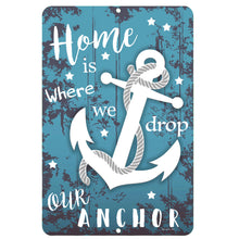 Load image into Gallery viewer, Dyenamic Art &#39;Home is Where We Drop Our Anchor&#39; metal sign featuring a bold white anchor with rope on a distressed blue wood-style background. A perfect nautical home decor piece.
