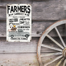 Load image into Gallery viewer, Farmers Market Metal Sign mounted on a barn-style wooden wall beside an antique wagon wheel, adding nostalgic country charm to kitchens, farmhouses, and produce markets.
