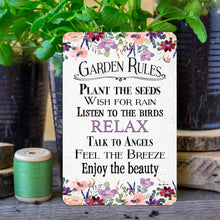 Load image into Gallery viewer, Dyenamic Art Garden Rules Metal Sign placed among fresh flowers and gardening tools for a cozy, rustic aesthetic.
