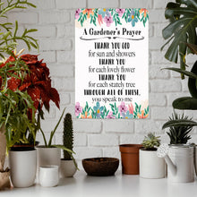 Load image into Gallery viewer, The Dyenamic Art Gardener’s Prayer metal sign displayed indoors on a white brick wall, surrounded by potted plants, succulents, and a watering can, creating a cozy garden-inspired decor setting.
