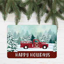 Load image into Gallery viewer, Dyenamic Art Red Truck Happy Holidays Metal Sign displayed under pine branches, creating a cozy rustic winter scene.
