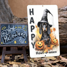 Load image into Gallery viewer, The Happy Howl-o-ween Metal Sign displayed in a rustic Halloween setup with a spooky chalkboard sign, fallen leaves, and a cozy autumn backdrop. A playful seasonal decoration for any space.
