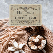 Load image into Gallery viewer, Rustic Hot Cocoa &amp; Coffee Bar Sign displayed with a warm knitted blanket, pine cones, and a cup of hot cocoa topped with marshmallows, creating the perfect cozy coffee corner ambiance.
