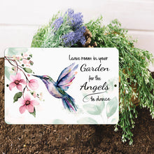Load image into Gallery viewer, Hummingbird Metal Sign placed in garden soil with fresh greenery, adding a spiritual touch to outdoor spaces.

