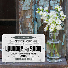 Load image into Gallery viewer, Funny Laundry Room Sign displayed on a rustic wood surface with fresh white flowers, blending humor with farmhouse-style decor.
