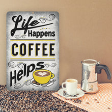 Load image into Gallery viewer, Life Happens Coffee Helps Metal Sign displayed on a table surrounded by coffee beans, a steaming cup of espresso, and a classic stovetop coffee maker, creating the perfect coffee-lover’s ambiance.
