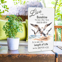 Load image into Gallery viewer, Dyenamic Art 'Live in the Sunshine' sign displayed on an outdoor patio with lush greenery, adding a relaxing and beachy vibe to the setting.
