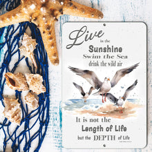Load image into Gallery viewer, Dyenamic Art 'Live in the Sunshine' sign placed among seashells and a starfish on a rustic blue wooden background, emphasizing its nautical charm.

