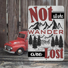 Load image into Gallery viewer, Close-up of the "Not All Who Wander Are Lost" adventure wall sign, showcased by a wooden fence and vintage red truck. Made of durable aluminum material with a distressed background.
