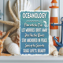 Load image into Gallery viewer, Oceanology Metal Sign displayed in a cozy beach-themed setting, surrounded by seashells, a lighthouse figurine, and nautical decor. A beautiful coastal-inspired sign that brings ocean wisdom and serenity to any space.
