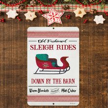Load image into Gallery viewer, Vintage Sleigh Rides Farmhouse Sign displayed among holiday decorations, including festive cookies, pinecones, and rustic wooden elements for a cozy Christmas feel.
