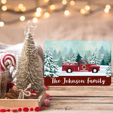 Load image into Gallery viewer, Personalized Red Truck Winter Scene Metal Sign placed among Christmas decorations and twinkling lights, enhancing festive home decor.
