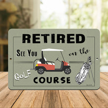 Load image into Gallery viewer, Dyenamic Art - Retired on the Golf Course Metal Sign – A Stylish Retirement Gift Displayed on a Wooden Table in a Cozy Golf Club Setting. A Great Addition to Any Golfer’s Home or Office.
