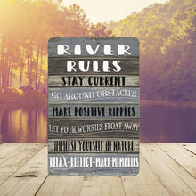 Load image into Gallery viewer, Rustic River Rules Metal Sign displayed near a peaceful river setting, adding charm and inspiration to lake homes, fishing cabins, and waterfront retreats.
