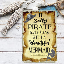 Load image into Gallery viewer, Nautical-themed Dyenamic Art Salty Pirate Lives with a Beautiful Mermaid Sign displayed on a coastal-inspired shelf with rope and fish decor, adding seafaring charm.
