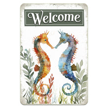 Load image into Gallery viewer, Dyenamic Art Seahorse Welcome Metal Sign featuring two watercolor seahorses in warm orange and cool blue tones facing each other with seaweed accents, set against a vintage-style whitewashed background.
