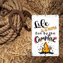 Load image into Gallery viewer, Life is S'more Fun by the Campfire Metal Sign placed in an outdoor camping setting, adding a fun and inviting touch to fire pit gatherings and camper setups.
