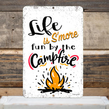 Load image into Gallery viewer, Life is S'more Fun by the Campfire Metal Sign displayed on a rustic wooden background, enhancing its vintage and cozy aesthetic for cabin and campsite decor.
