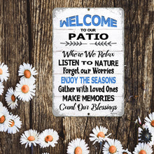Load image into Gallery viewer, A close-up of the Welcome to Our Patio sign, highlighting its weathered white wood design, bold blue and black typography, and motivational wording.
