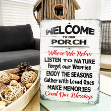 Load image into Gallery viewer, The Dyenamic Art Welcome to Our Porch sign displayed in a cozy indoor setting with a wooden tray, pinecones, and a rustic birdhouse, adding warmth to the decor.
