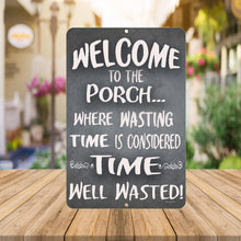 Load image into Gallery viewer, A close-up of the Dyenamic Art Welcome to Our Porch metal sign, showcasing its bold white typography on a dark gray textured background with decorative flourishes.
