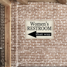 Load image into Gallery viewer, Women&#39;s Restroom Metal Sign with a left-pointing arrow mounted on an exposed brick wall, adding a vintage touch to restroom wayfinding decor.
