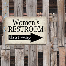 Load image into Gallery viewer, Women's Restroom directional sign with a right-pointing arrow affixed to a rustic wooden fence, blending functionality with farmhouse aesthetics.
