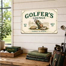Load image into Gallery viewer, A rectangular vintage-style metal sign reading 'GOLFER'S LOUNGE' with an illustration of a golf bag, clubs, and golf ball, displayed on a white shiplap wall above a wooden table with golf props including a tee box, books, and a club bag.
