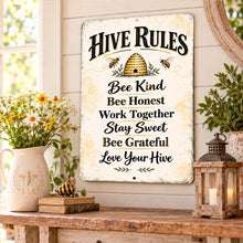 Load image into Gallery viewer, Honeybee farmhouse metal sign leaning against a light wall on a wooden table beside a potted plant and warm rustic home accessories.
