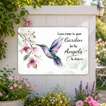 Load image into Gallery viewer, Hummingbird angel metal sign displayed on a white garden fence surrounded by flowers and greenery
