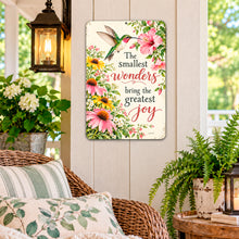 Load image into Gallery viewer, Hummingbird garden wall sign hanging on a light-colored porch wall beside a vintage lantern, greenery, and cottage garden decorations.
