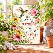 Load image into Gallery viewer, Inspirational hummingbird metal sign displayed on a sunny garden potting bench surrounded by blooming flowers, gardening gloves, and rustic accessories.
