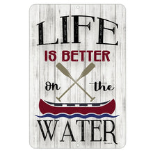 Load image into Gallery viewer, Rustic metal sign that reads “Life Is Better On the Water” with crossed oars and a red canoe, displayed on a whitewashed wood background
