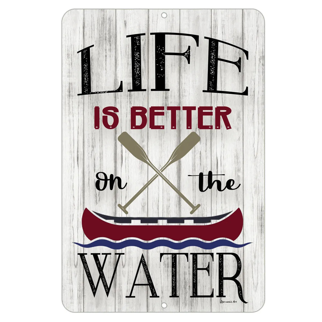 Rustic metal sign that reads “Life Is Better On the Water” with crossed oars and a red canoe, displayed on a whitewashed wood background