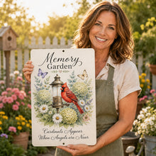 Load image into Gallery viewer, Woman holding a cardinal Memory Garden memorial sign outdoors beside colorful flowers and garden greenery.

