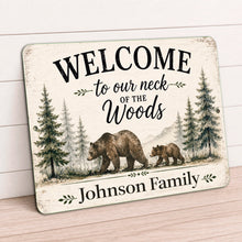 Load image into Gallery viewer, A personalized rustic wooden sign leaning against a white shiplap wall on a light wood floor. The sign features a distressed cream background with black text reading 'WELCOME to our neck of the Woods' and 'Johnson Family,' along with an illustration of a bear family, pine trees, and mountains.
